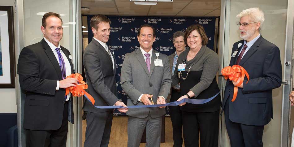 Surrounded by four business people, a businessman cuts the ribbon to the newly-renovated floor of Memorial Health's behavioral sciences building